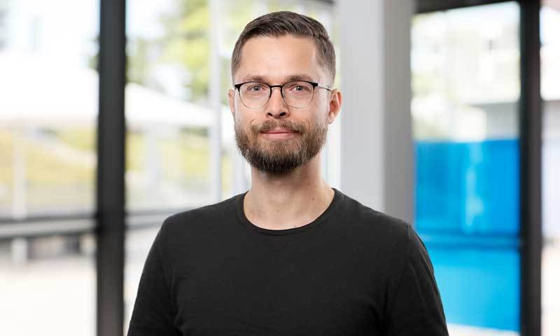Ein Mann mit Brille steht in einem Foyer.