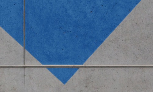 Blaues Dreick auf einer Betonwand bedeckt den oberen Teil der sichtbaren Wandlfäche