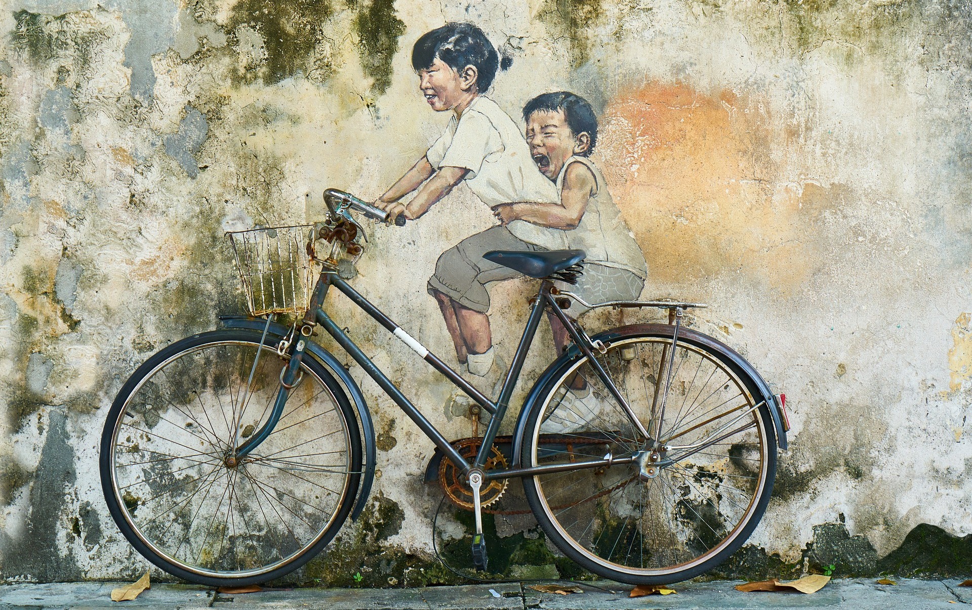 Two Boys are riding an old bicycle