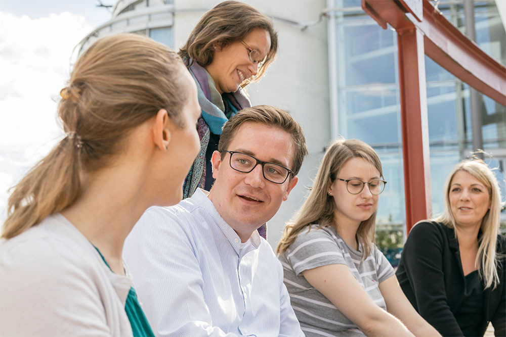 Gruppe von Forschenden sitzend auf Außengelände