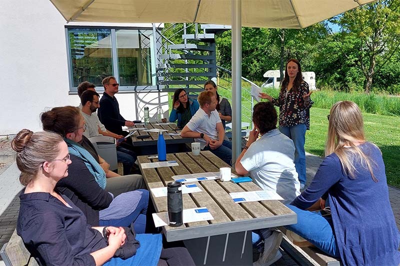 Doctoral students and postdocs sitting outside under parasol