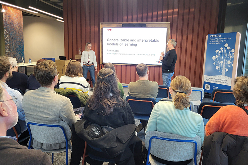 Tanja Käser und Marcus Specht vor einem Vortrags-Bildschirm, im Vordergrud Publikum