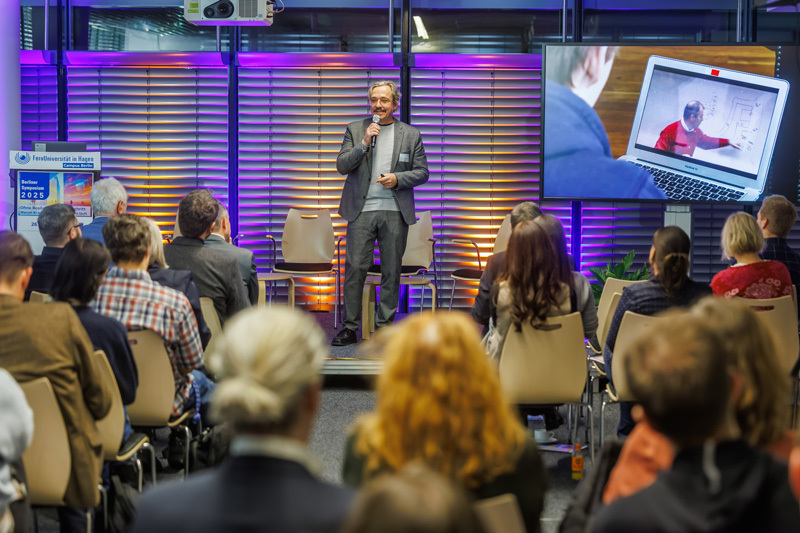 Marcus Specht auf dem Podium, davor Publikum von hinten