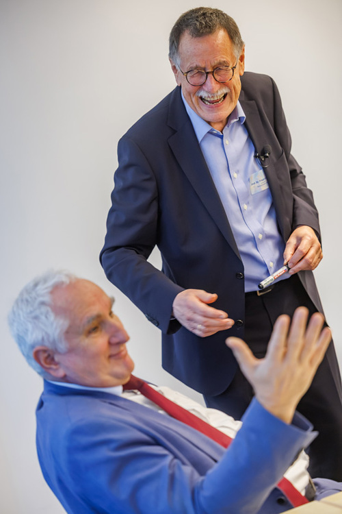 Ulrich Bartosch hat den rechten Arm zur Seite weit geöffnet, Friedrich Hesse lacht im Hintergrund.