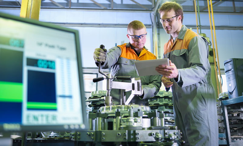 Two scientists working on some machinery in an industrial lab