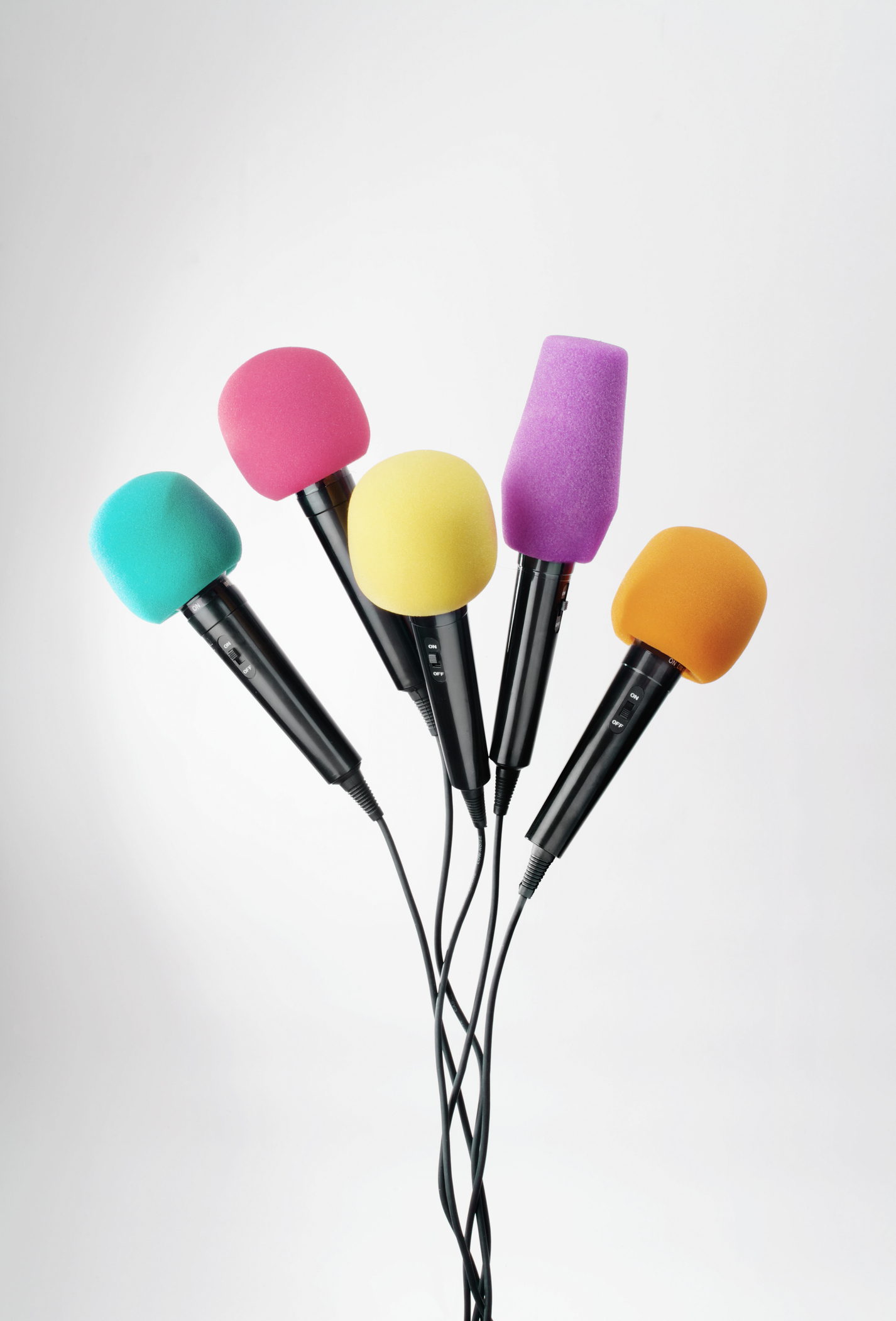 Fünf Mikrofone vor einem weißen Hintergrund. Die Köpfe der Mikrofone sind türkis, pink, gelb, lila und orange.