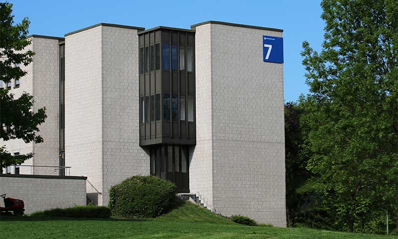 Foto des Gebäude 7 mit Bäumen und Wiese im Vordergrund