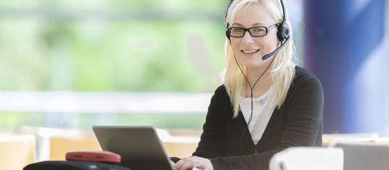 Frau mit Headset am Laptop
