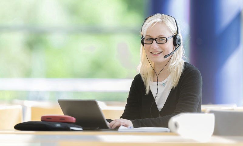 Frau am Laptop mit Headset