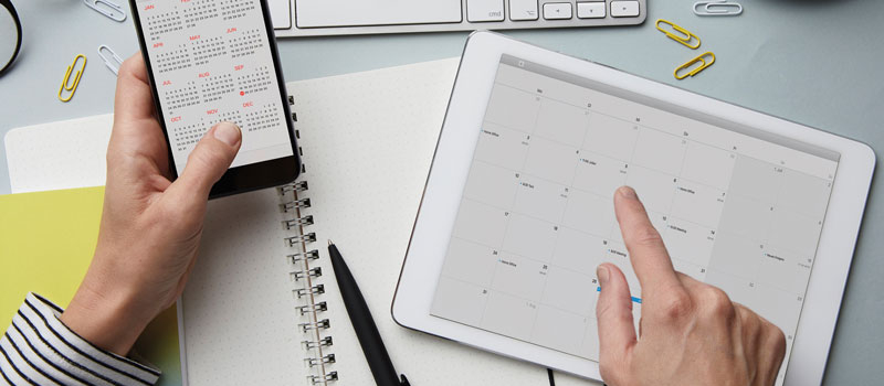 Person checking their calendar on a mobile phone and a tablet