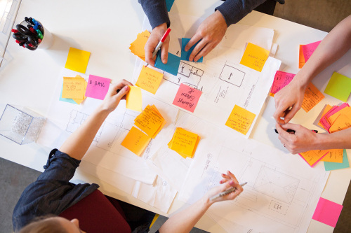 Mehrere Personen arbeiten mit Post-Its an einem Tisch.