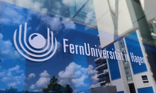 FernUni-Logo auf Glasscheibe (mit Spiegelung von Wolken und dem AVZ-Gebäude im Anschnitt)
