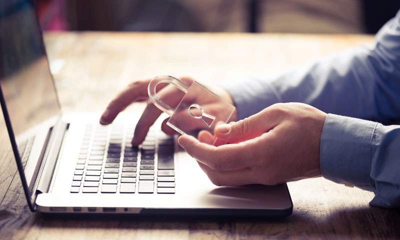 Person mit Schloss in der Hand am Laptop