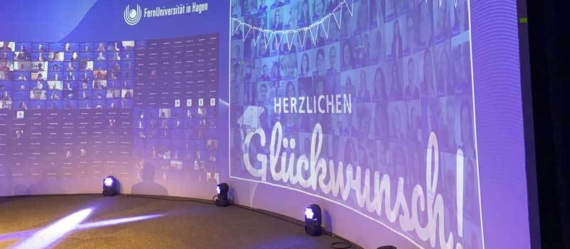 Digitale Wand mit vielen Personenfotos und dem Schriftzug „Herzlichen Glückwunsch!“