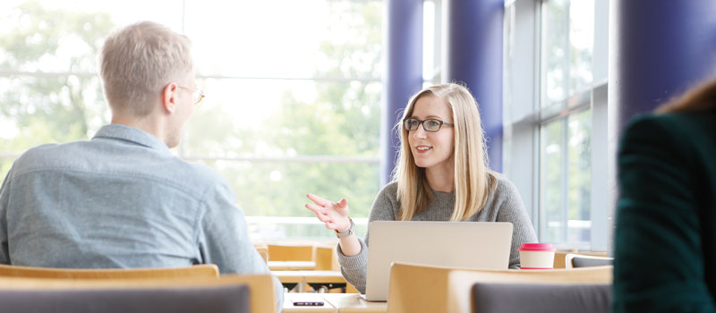 Frau und Mann sitzen am Tisch und tauschen sich aus.