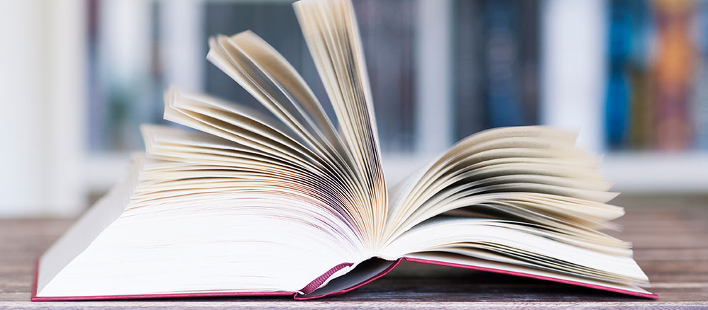 Aufgeschlagenes Buch vor Buecherregal