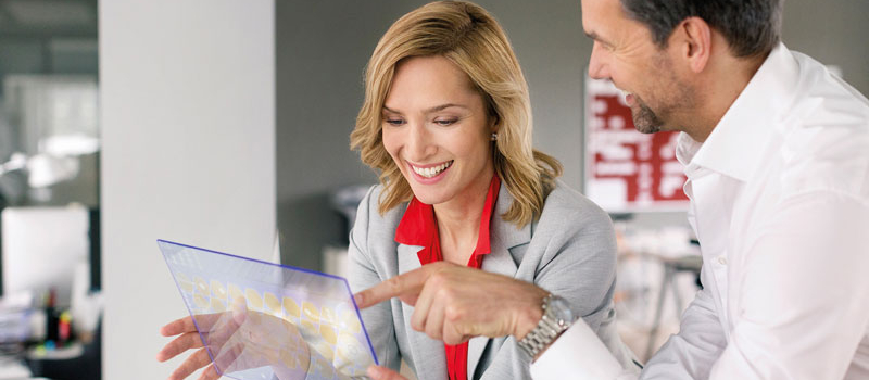 zwei Menschen zeigen etwas mit einem transparentem Touchscreen