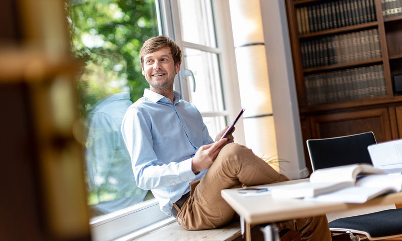 Man sitting on a windowsill with a tablet