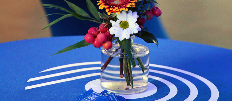 Eine Vase mit Blumen auf einem Tisch mit FernUni Logo