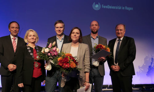 Sechs Personen stehen mit Blumensträußen auf einer Bühne