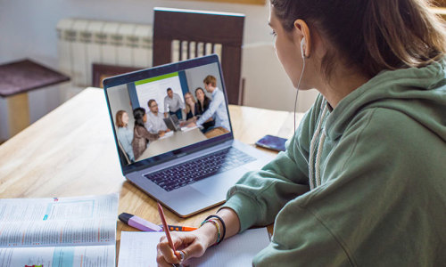 eine Studentin blickt auf ein Notebook, dort läuft eine Lehrveranstaltung der FernUni