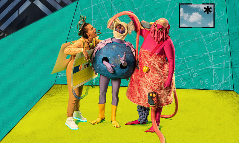 Three figures in colorful costumes stand in front of a surreal film set