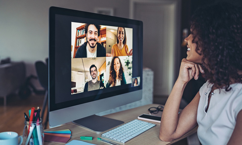 A woman sits at a monitor and watches a video conference