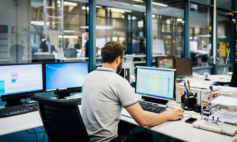 Mann arbeitet in Fabrik an Computer