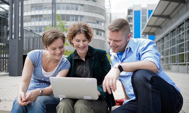 Studierende mit Notebook auf dem Campus