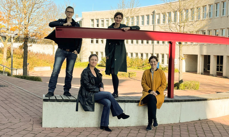 Gruppenfoto: Vier Personen auf dem Campus