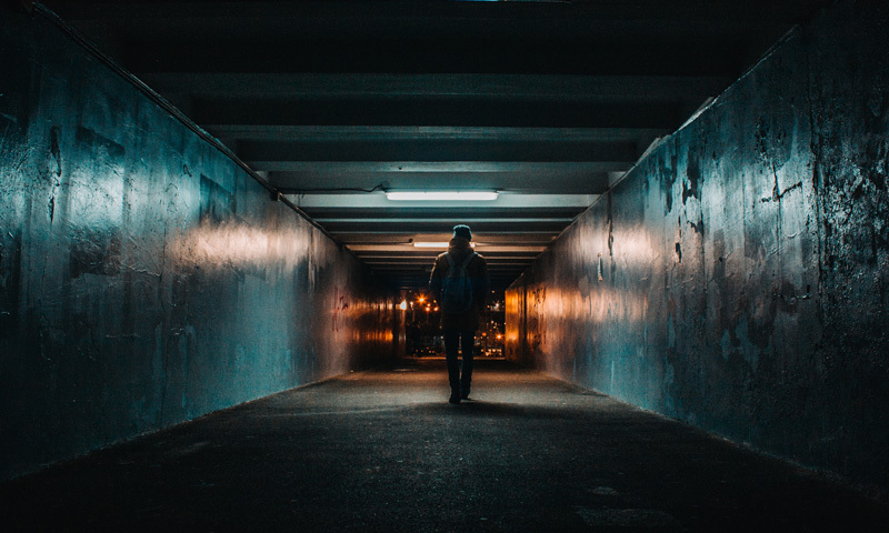 Mann läuft durch dunklen, einsamen Tunnel