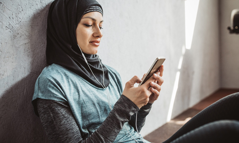 Frau mit Kopftuch schaut auf Smartphone