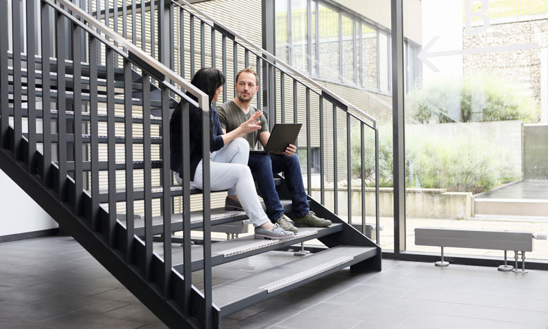 Ein Mann und eine Frau unterhalten sich auf einer Treppe.