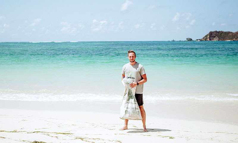 Christoph Schulz mit Müllsack an einem Strand