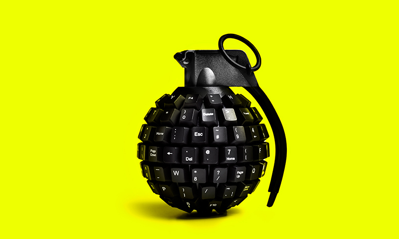 Symbolbild: Eine Handgranate, die aus einer Tastatur geformt ist vor gelbem Hintergrund.