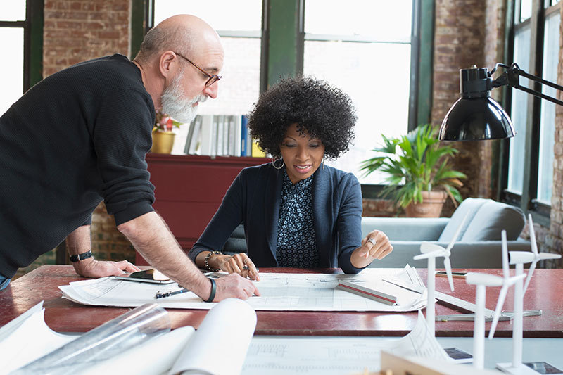 A man and a woman discussing some papers that lying on a desk