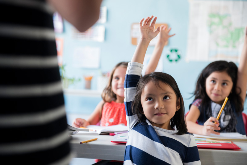 Kinder in einer Schulklasse melden sich