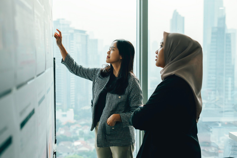 Zwei Frauen arbeiten in Büro vor indonesischer Stadtkulisse