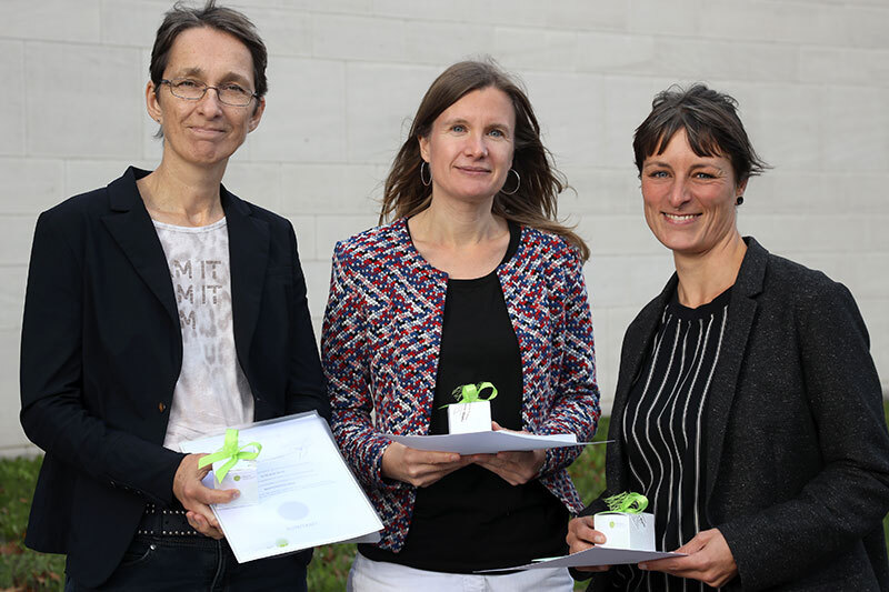 Drei Frauen halten eine Auszeichnung in der Hand.