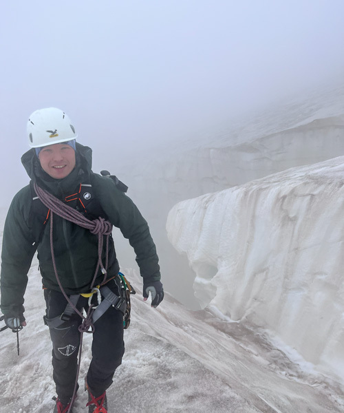 Mann mit Bergsteigerausrüstung auf nebligem Fels