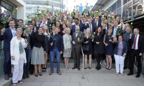 Gruppe von Alumni mit Rosen auf der Treppe vor der Mensa