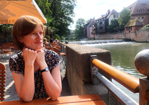 Conny Ebert sitzt am Tisch an einem Fluss