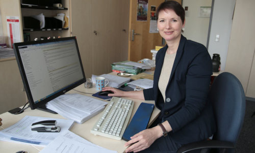 Eine Frau sitzt am Schreibtisch vor einem Computer .