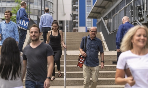 Studierende auf einer Treppe auf dem Campus der FernUni, in der Mitte geht ein Mann die Stufen runter