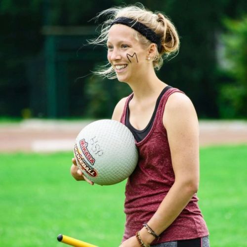 Eine Frau hält mit der einen Hand einen Ball fest, mit der anderen hält sie einen Plastikstab.