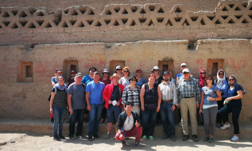 Eine Gruppe mit rund 20 Personen steht vor einer Ruine in Peru.