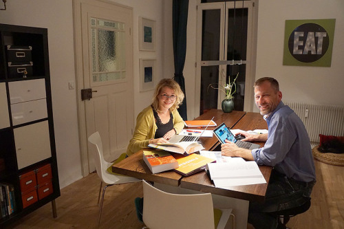 Abdreas Dütz und seine Partnerin sitzen an einem Küchentisch mit vielen Studienmaterialien und lernen gemeinsam für ihre unterschiedlichen Studien.