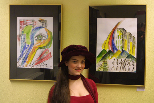 Eine junge Frau in rotem Kleid mit großem Hut vor selbstgelten Bildern