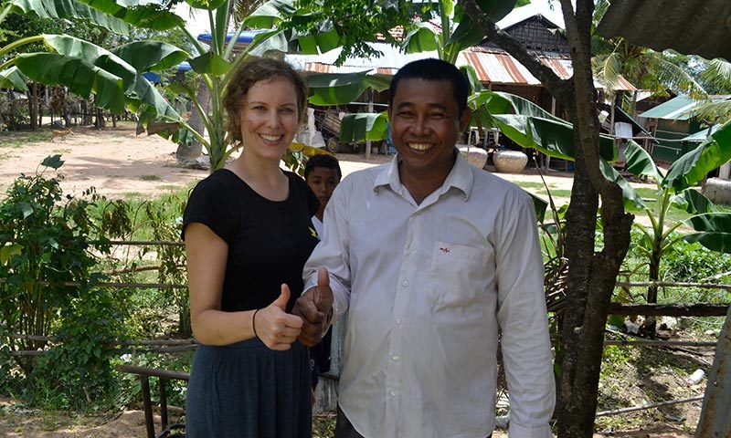 Julia Beideck steht neben einem Mann aus Kambodscha. Beide lächeln und strecken einen Daumen nach oben.