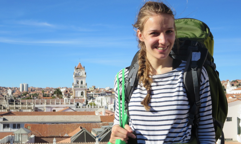 Charlotte Drath mit Rucksack über den Dächern einer Stadt